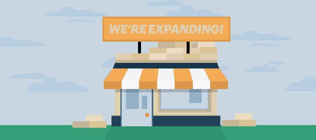 A sign on top of a small shop reads “We’re Expanding!”