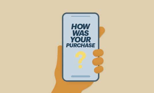 A hand holds a smartphone whose screen reads, “How was your purchase?”