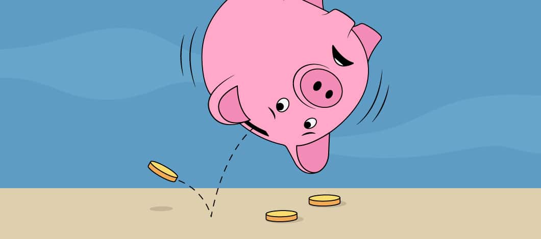 Upside down pink piggy bank with coins falling out