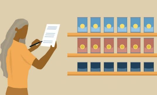 A businesswoman stands next to shelves filled with cans. She is taking stock of her inventory, jotting notes on her clipboard.