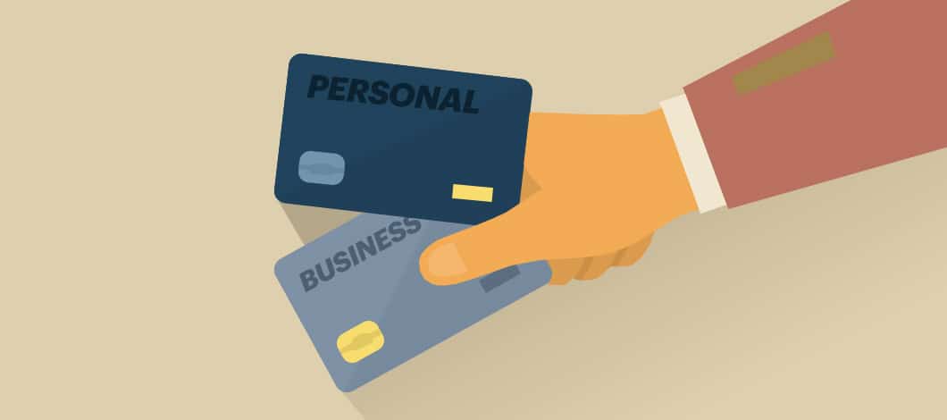 A hand holds two credit cards. One is labeled “Personal” and the other is labeled “Business.”