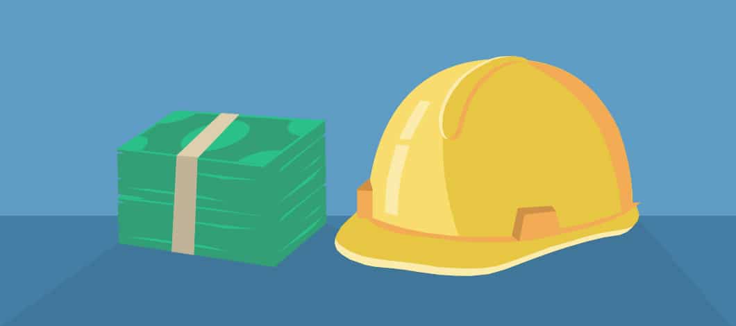 A stack of money rests next to a hard hat.