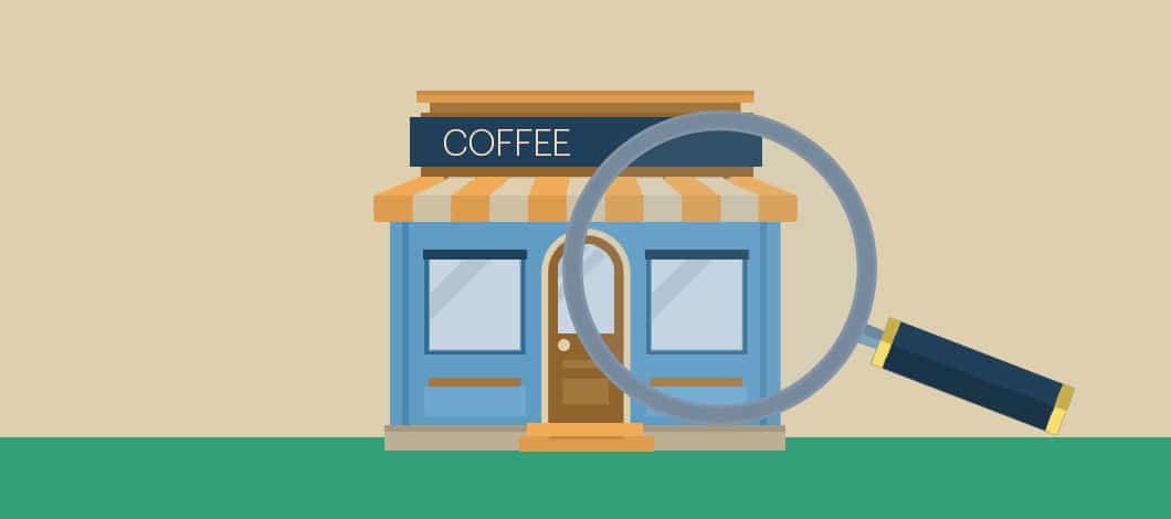 A giant magnifying glass inspects a small coffee shop.