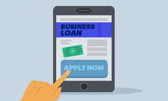 A hand is about to tap on the big “Apply Now” button of a computer tablet screen displaying a web page labeled “Business Loan.”