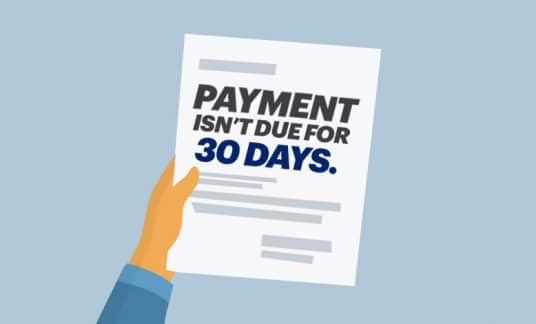 A hand holds a paper notice that reads “Payment Isn’t Due for 30 Days.”