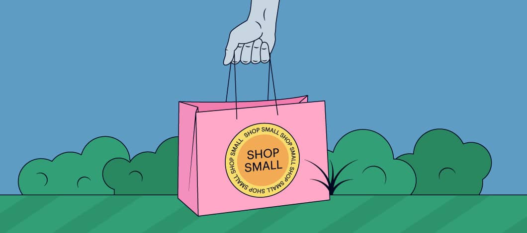 A hand holds a shopping bag that reads “Shop Small.”