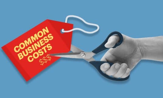 A price tag labeled “Common Business Costs” is about to be cut by a pair of scissors.