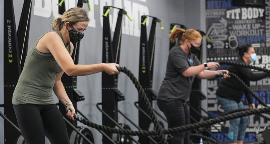 Three women at the Fit Body Boot Camp gym participating in a ropes exercise