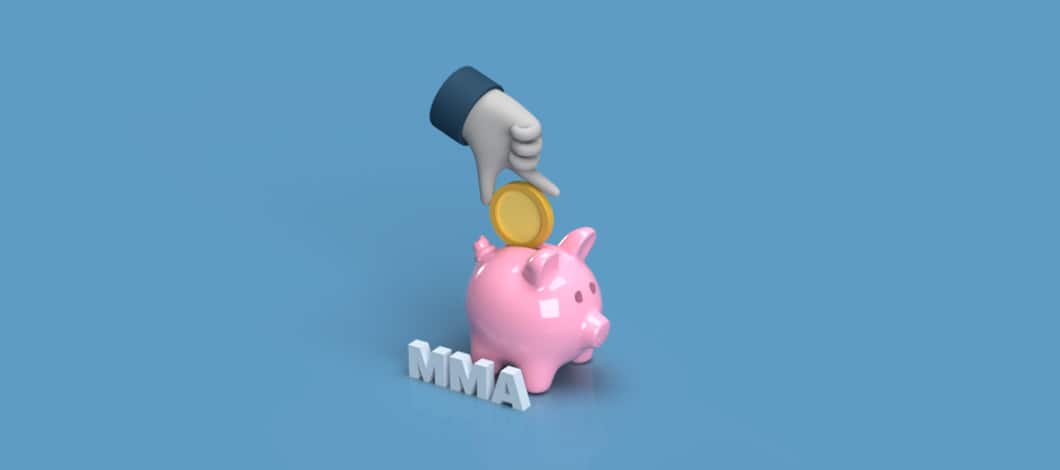 A hand puts a coin into the slot of a piggy bank labeled “MMA.”